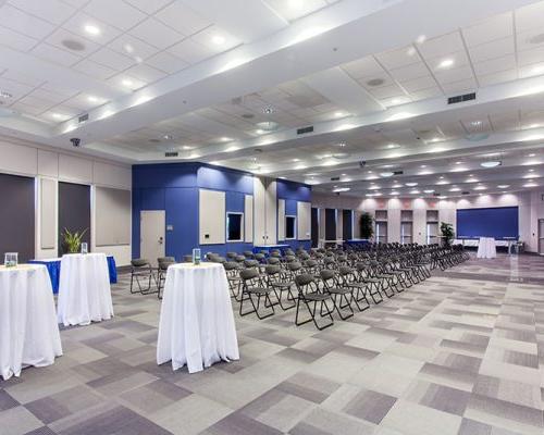 Interior photo of a large room with chairs and bar height tables ready for a presentation.